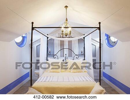 Stock Image - Chandelier over four poster bed in luxury bedroom. Fotosearch
