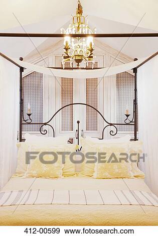 Chandelier over four poster bed with yellow linens View Large Photo Image Stock Photo - Chandelier over four poster bed with yellow linens. Fotosearch