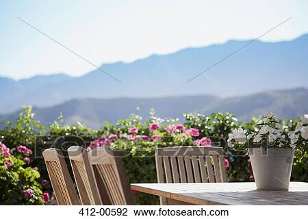 Stock Image - Flowers around patio table overlooking mountains. Fotosearch