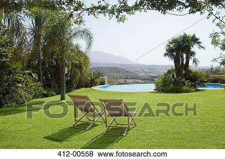 Lawn chair in grass overlooking swimming pool View Large Photo Image Stock Photo - Lawn chair in grass overlooking swimming pool. Fotosearch