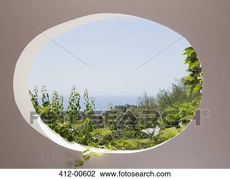 Stock Image - View of garden through oval window. Fotosearch