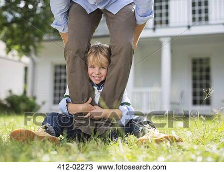 Boy peeking out from between father's legs View Large Photo Image Stock Image - Boy peeking out from between father's legs. Fotosearch