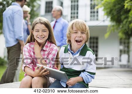 Children using digital tablet together outdoors View Large Photo Image Stock Image - Children using digital tablet together outdoors. Fotosearch