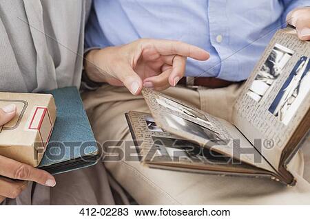 Couple looking through photo album together View Large Photo Image Stock Image - Couple looking through photo album together. Fotosearch