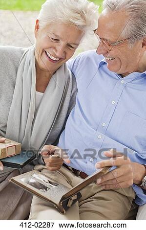 Couple looking through photo album together View Large Photo Image Stock Photo - Couple looking through photo album together. Fotosearch