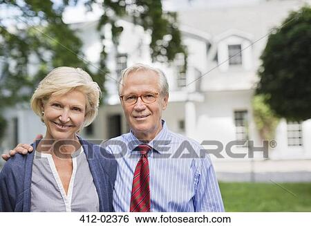 Couple smiling together outside house View Large Photo Image Stock Photograph - Couple smiling together outside house. Fotosearch