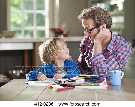 Stock Image - Father and son doing homework at kitchen table. Fotosearch