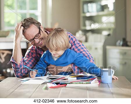 Stock Photograph - Father and son doing homework at kitchen table. Fotosearch
