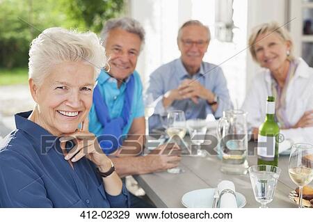 Friends smiling at table outdoors View Large Photo Image Stock Photo - Friends smiling at table outdoors. Fotosearch