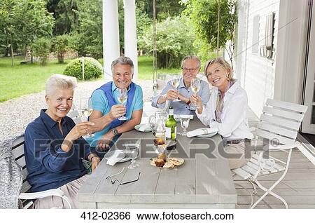 Stock Photograph - Friends toasting each other with wine at table. Fotosearch