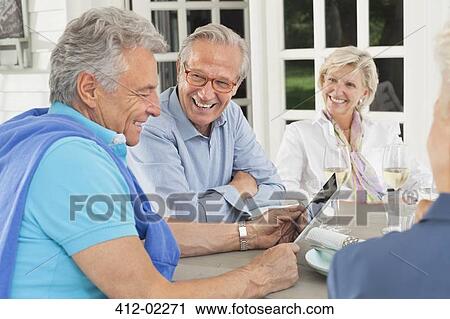 Stock Image - Friends using digital tablet together. Fotosearch