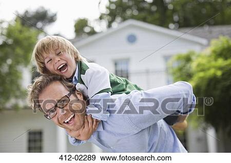 Stock Photo - Man carrying son piggyback outdoors. Fotosearch