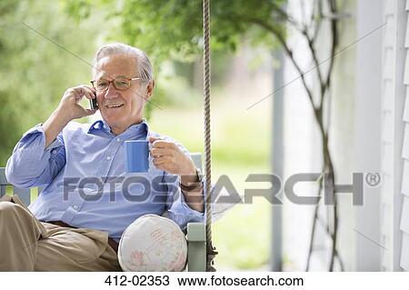 Man talking on cell phone in porch swing View Large Photo Image Stock Image - Man talking on cell phone in porch swing. Fotosearch