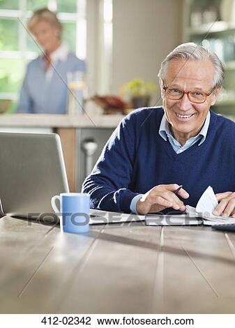 Man using laptop at kitchen table View Large Photo Image Stock Image - Man using laptop at kitchen table. Fotosearch