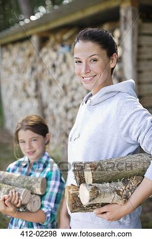 Stock Photo - Mother and daughter carrying firewood outdoors. Fotosearch