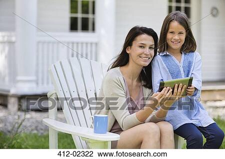 Stock Image - Mother and daughter using digital tablet outdoors. Fotosearch