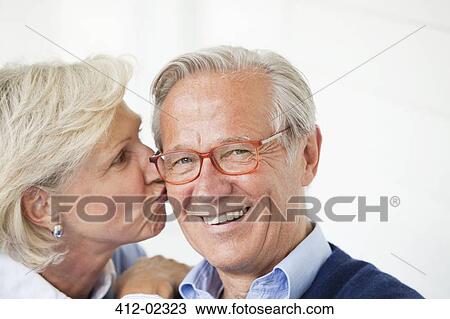 Stock Image - Smiling woman kissing husband. Fotosearch