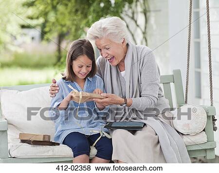 Woman giving granddaughter present in porch swing View Large Photo Image Stock Photo - Woman giving granddaughter present in porch swing. Fotosearch