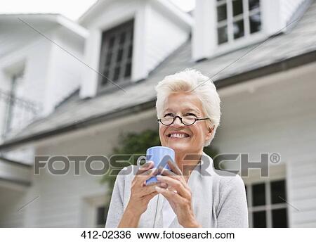 Stock Photograph - Woman having cup of coffee outdoors. Fotosearch
