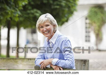 Picture - Woman leaning on wooden fence. Fotosearch