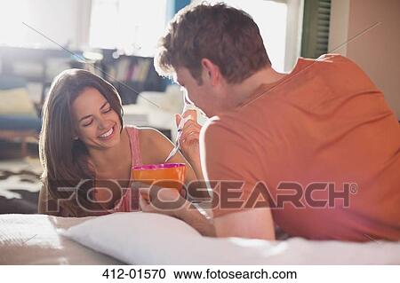 Stock Image - Couple eating breakfast in bed together. Fotosearch