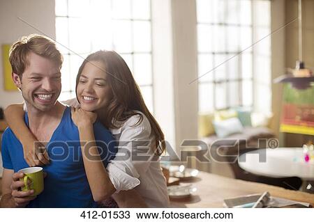Stock Image - Couple hugging in kitchen. Fotosearch