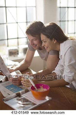 Couple reading newspaper together at breakfast View Large Photo Image Stock Photo - Couple reading newspaper together at breakfast. Fotosearch