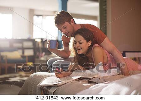 Couple reading newspaper together on bed View Large Photo Image Stock Image - Couple reading newspaper together on bed. Fotosearch