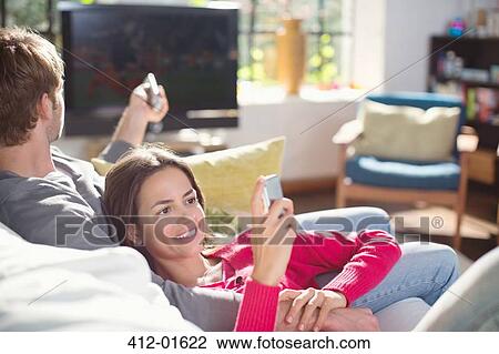 Stock Image - Couple relaxing on sofa together. Fotosearch