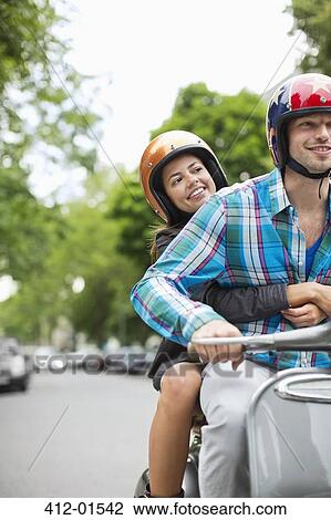 Couple riding scooter together View Large Photo Image Stock Image - Couple riding scooter together. Fotosearch