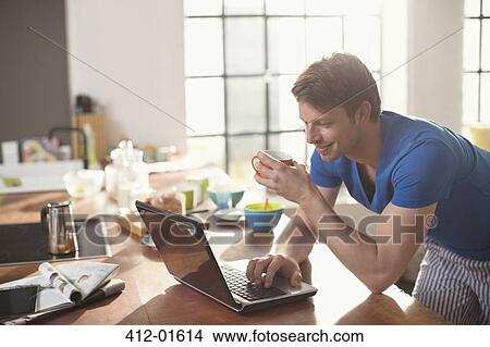 Picture - Man using laptop with cup of coffee. Fotosearch