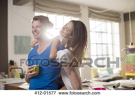 Stock Photo - Smiling couple hugging in kitchen. Fotosearch