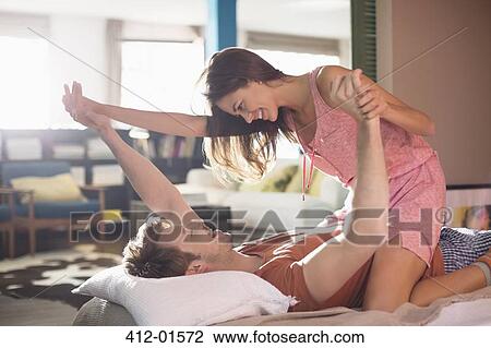 Smiling couple playing on bed View Large Photo Image Stock Image - Smiling couple playing on bed. Fotosearch