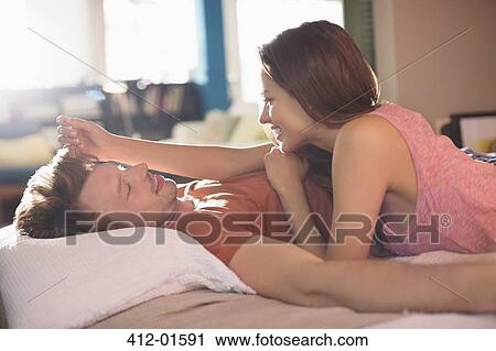 Smiling couple relaxing on bed View Large Photo Image Stock Image - Smiling couple relaxing on bed. Fotosearch