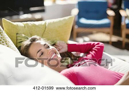Stock Photo - Smiling woman relaxing on sofa. Fotosearch