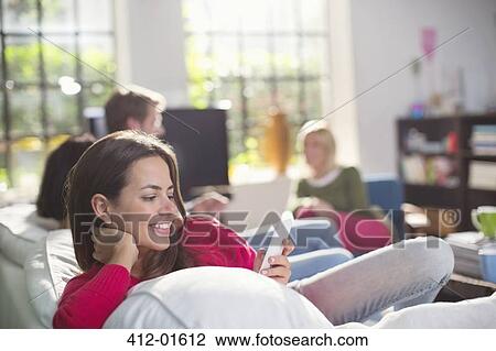 Smiling woman using cell phone on sofa View Large Photo Image Stock Image - Smiling woman using cell phone on sofa. Fotosearch