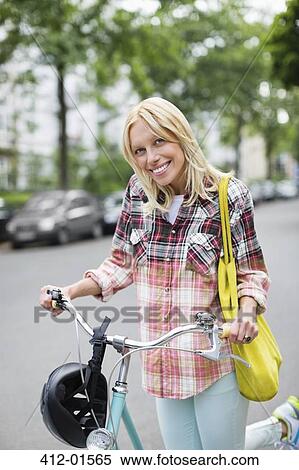 Stock Photography - Woman pushing bicycle on city street. Fotosearch