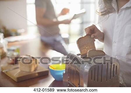 Woman putting bread in toaster View Large Photo Image Stock Photo - Woman putting bread in toaster. Fotosearch