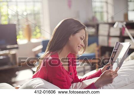 Woman reading magazine on sofa View Large Photo Image Stock Photograph - Woman reading magazine on sofa. Fotosearch