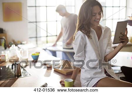 Stock Photograph - Woman using digital tablet in kitchen. Fotosearch