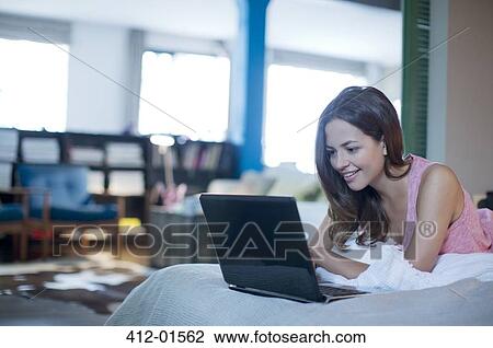 Woman using laptop on bed View Large Photo Image Stock Image - Woman using laptop on bed. Fotosearch
