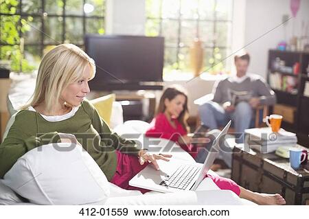 Stock Photo - Woman using laptop on sofa. Fotosearch