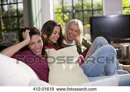 Stock Photo - Women laughing together on sofa. Fotosearch