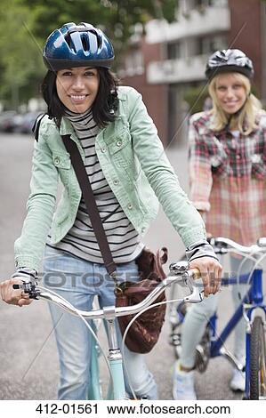 Women pushing bicycles on city street View Large Photo Image Stock Image - Women pushing bicycles on city street. Fotosearch