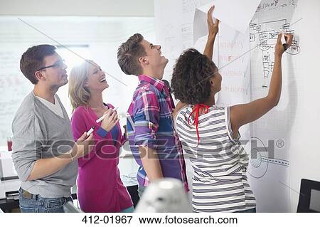 Stock Photo - Business people reading blueprints in office. Fotosearch
