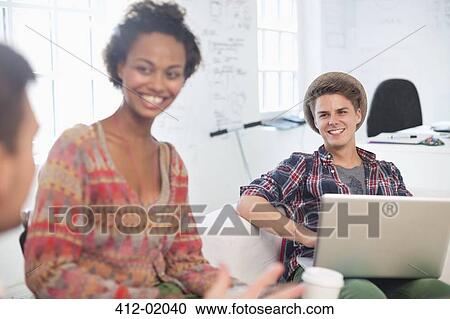 Stock Image - Business people talking on sofa in office. Fotosearch