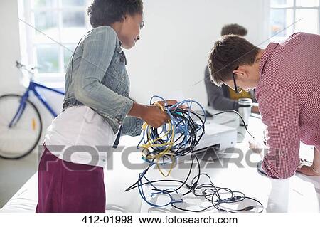 Stock Photo - Business people untangling cords in office. Fotosearch