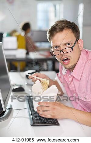 Stock Photography - Businessman eating Chinese food at desk. Fotosearch