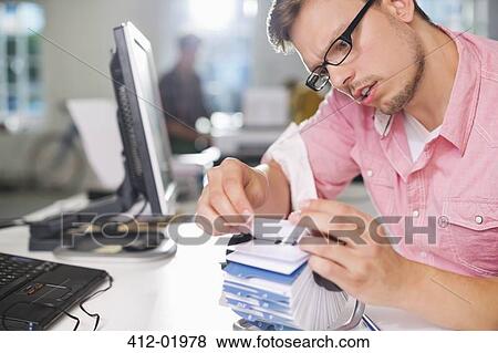 Stock Photo - Businessman searching for address on desk. Fotosearch