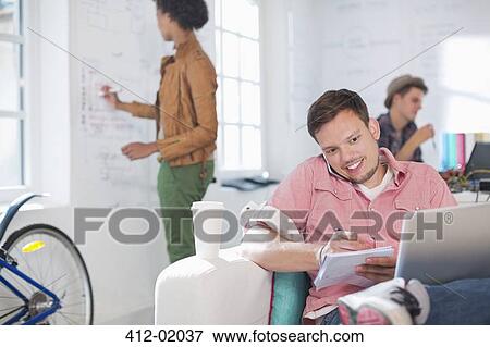 Stock Photo - Businessman taking notes on phone in office. Fotosearch